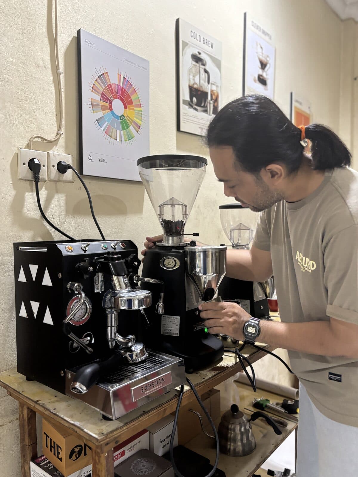 Barista menarik espresso di bar dengan roda rasa kopi terpasang di dinding
